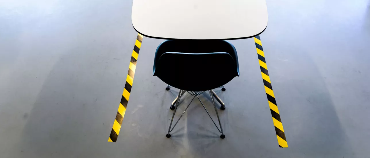 Närbild på stol och bord placerade inom gulsvart markering i golvet. Foto.