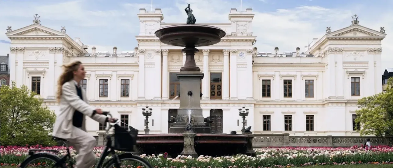 Tjej cyklar förbi universitetshuset. Bild från film.