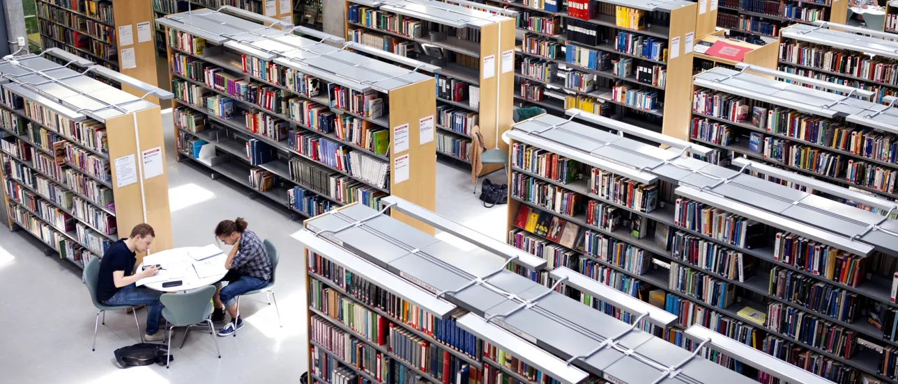 Rader med bokhyllor på ett bibliotek.
