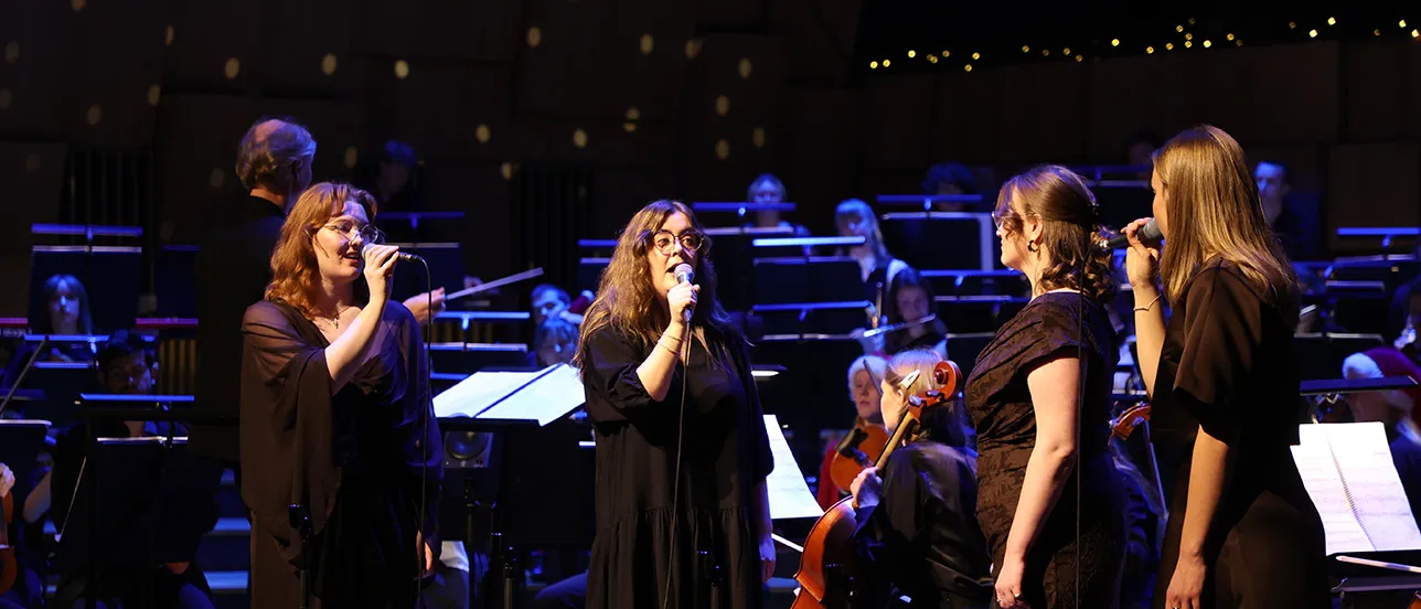 Två personer sjunger i en mikrofon. Foto.