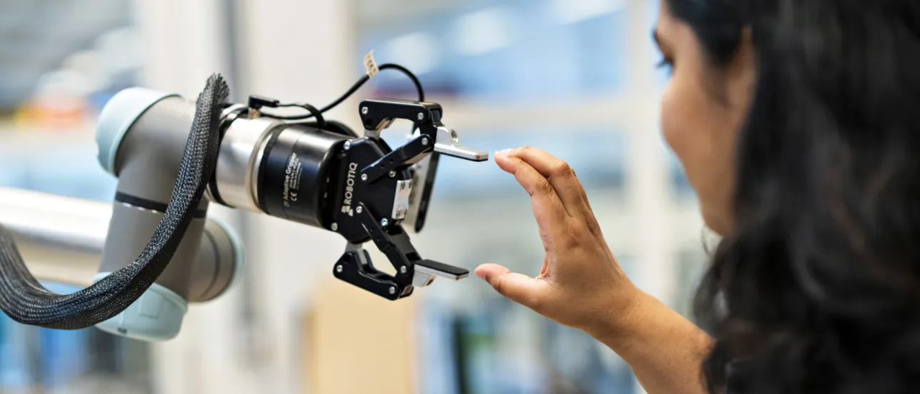 En människa håller sin hand vid en robotarm.