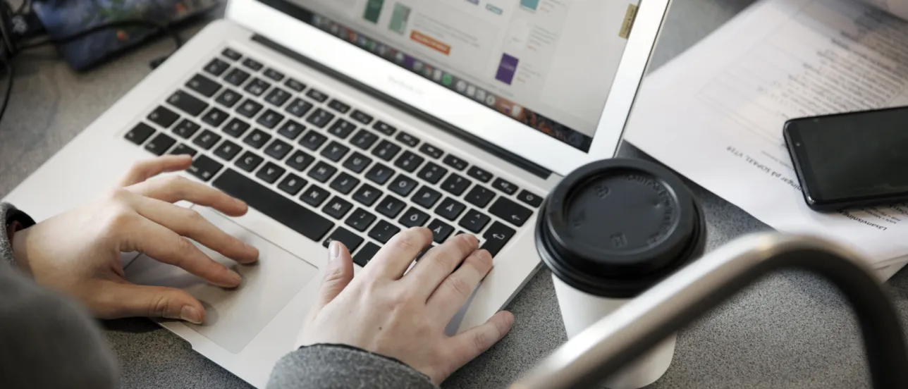 En person skriver på en laptop.