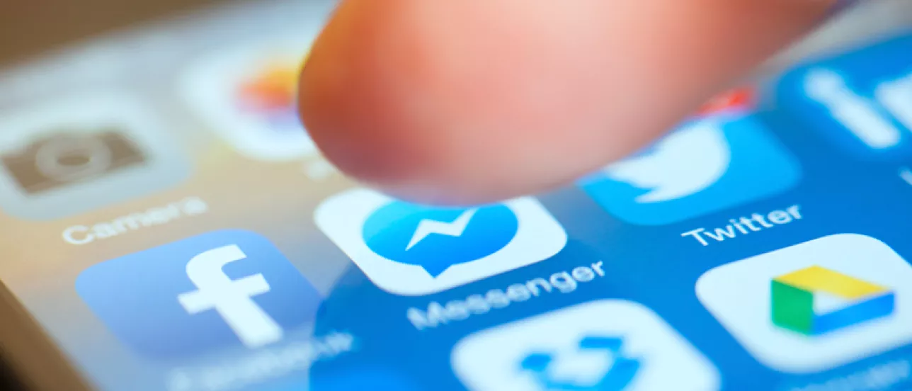 Bilden visar ett finger som rör sig ovanför en mobilskärm. Skärmen visar olika appar som är populära idag.