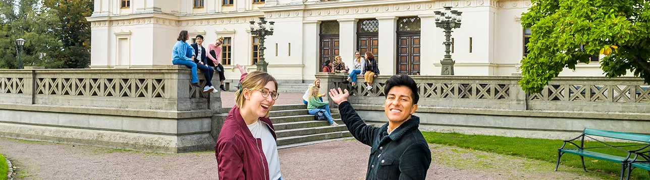 Två studenter bjuder in till samtal utanför universitetshuset. Foto.