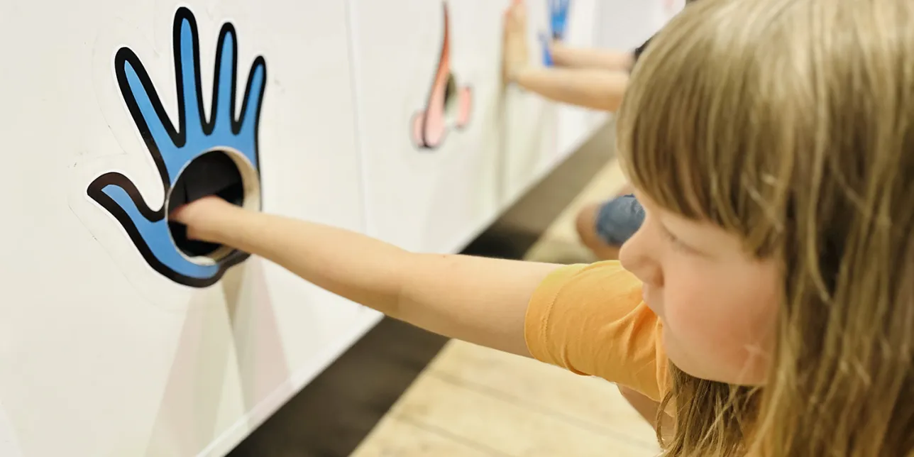 Flicka med handen i Sinneshyllan på Vattenhallen. Foto.