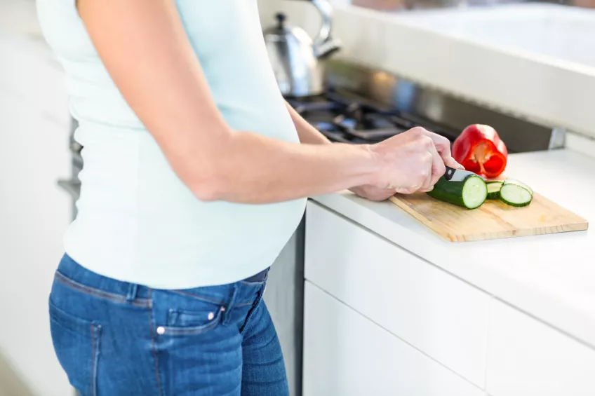 Gravid kvinna skär grönsaker