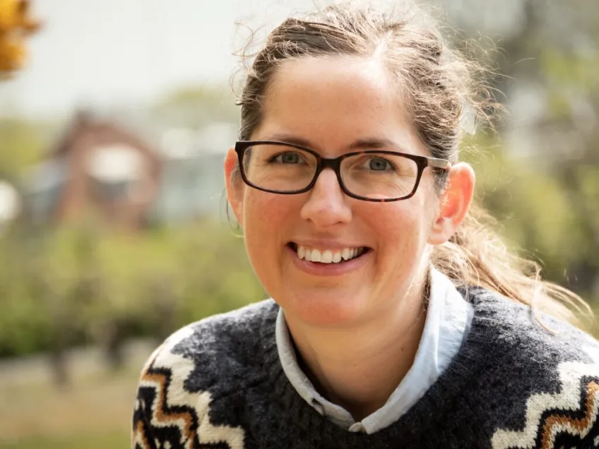 Porträtt utomhus av ung kvinna med glasögon och uppsatt hår. Foto.