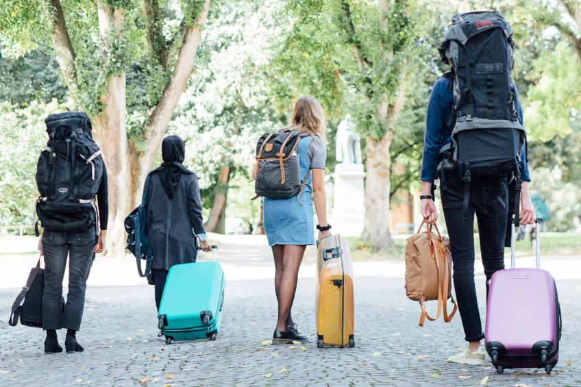 Studenter går med resväskor och ryggsäckar. Foto: Eric Hertz.