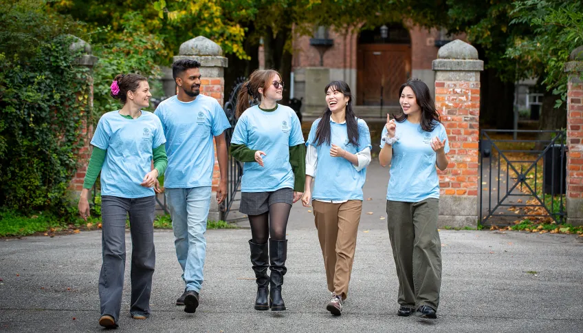 Fem internationella mentorer går och pratar. Foto.