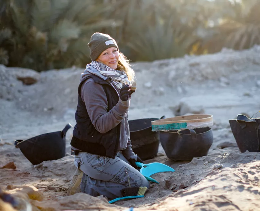 Kvinna sitter och gräver i sand