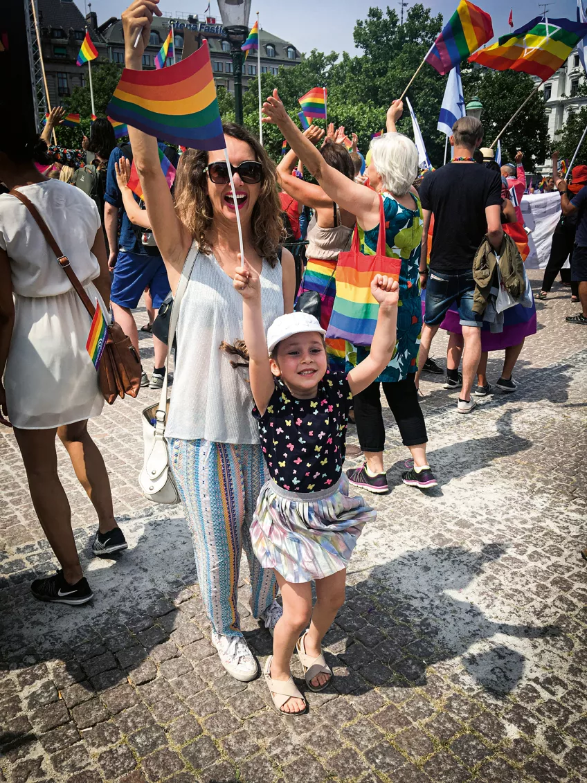 Kvinna och barn viftar med regnbågsflaggor