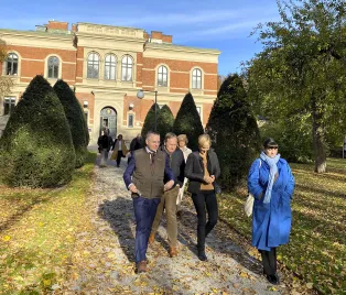 En grupp personer promenerar framför ett hus. 